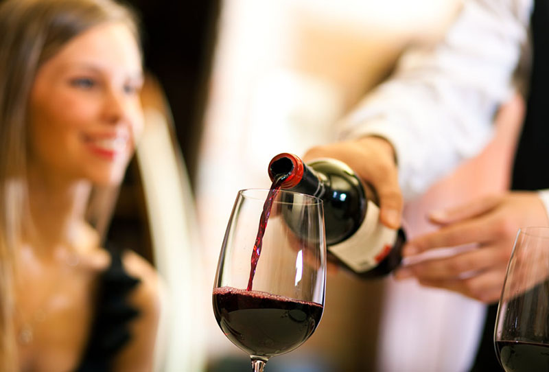 Waiter serving red wine
